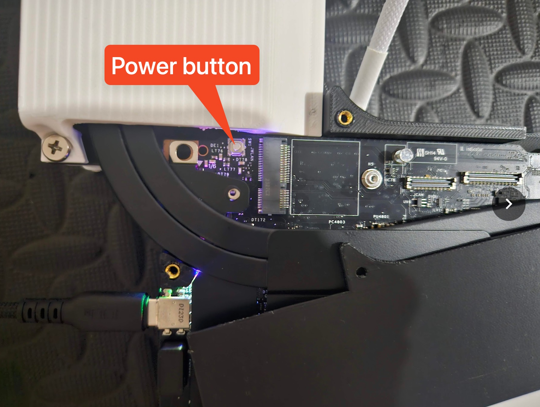 Close-up of the Framework 16 power button accessible through a single corner screw in the 3D-printed cover.